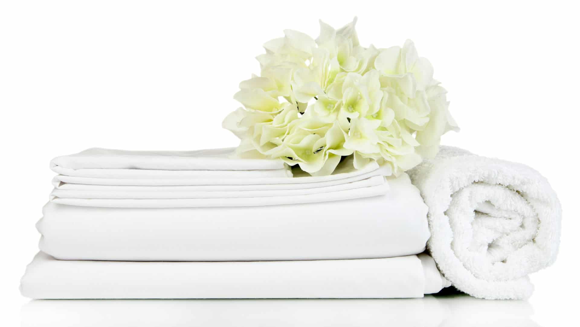 Stack of clean bedding sheets and towels isolated on white Austin